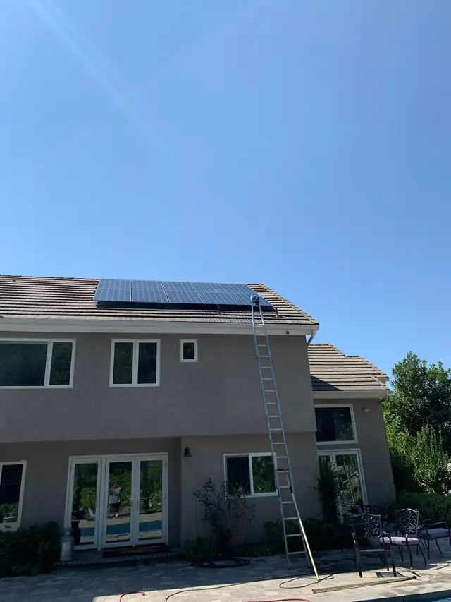 Two-storey home with a ladder raised to the solar panels on the roof