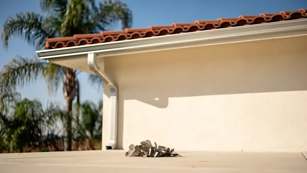 Clean white gutter and downspout under a terracotta tile roof
