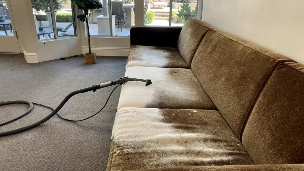Fabric sofa mid-clean with a cleaned stripe across the cushions