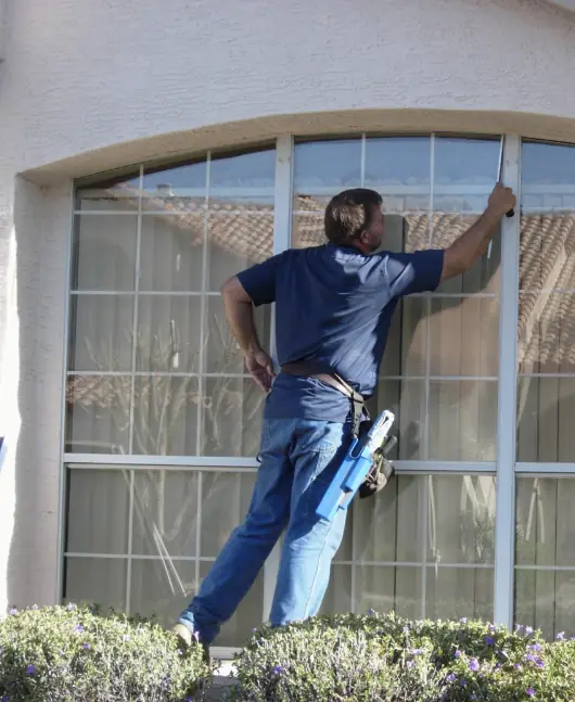 Alan's technician cleaning a tall arched window from the garden bed