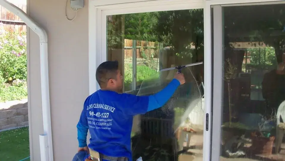 Alan's technician in a company shirt cleaning a sliding glass door